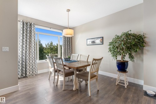 Expansive window with bright natural light, wood-finish flooring, recessed lighting, and a drum pendant fixture - 3334 Parker Loop Sw, Edmonton, AB 