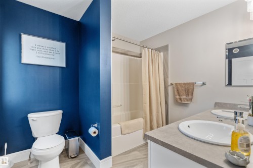 Bathroom featuring a dual vanity with undermount sinks, a combination shower and tub, and light-toned flooring - 3334 Parker Loop Sw, Edmonton, AB 