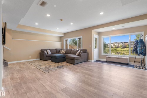 Recessed lighting, light wood-finish flooring, and large windows with a prominent water backdrop - 3334 Parker Loop Sw, Edmonton, AB 