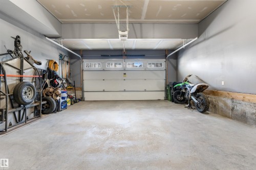 Spacious garage with a concrete floor, painted gray walls, and a white overhead door with upper window inserts - 3334 Parker Loop Sw, Edmonton, AB 