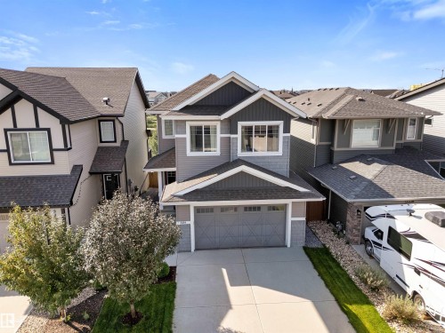 Two-story exterior with a two-car garage, gray siding, and a paved driveway - 3334 Parker Loop Sw, Edmonton, AB 