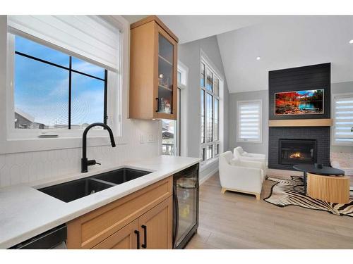 10 Songbird Green, Sylvan Lake, AB - Indoor Photo Showing Kitchen With Fireplace With Double Sink