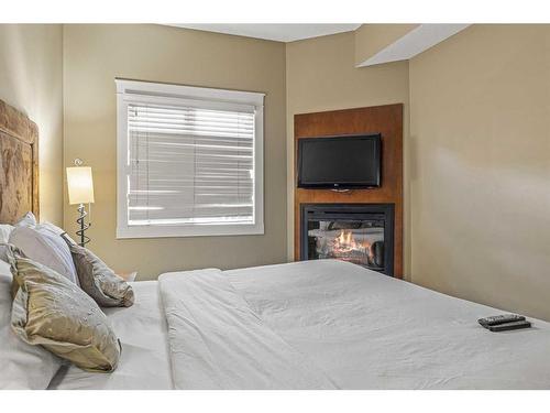 301-191 Kananaskis Way, Canmore, AB - Indoor Photo Showing Bedroom With Fireplace