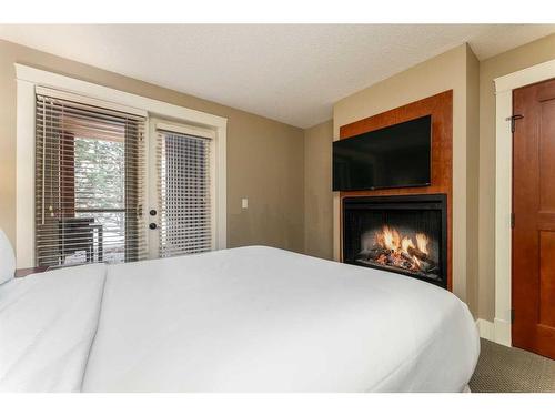 121-173 Kananaskis Way, Canmore, AB - Indoor Photo Showing Bedroom With Fireplace