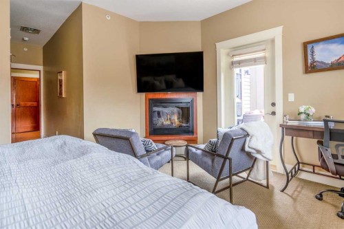 406-187 Kananaskis Way, Canmore, AB - Indoor Photo Showing Bedroom With Fireplace