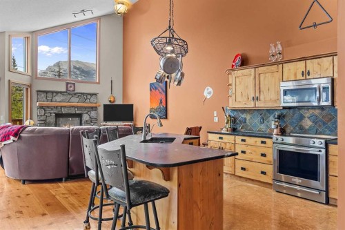 B-243 Three Sisters Drive, Canmore, AB - Indoor Photo Showing Kitchen With Fireplace