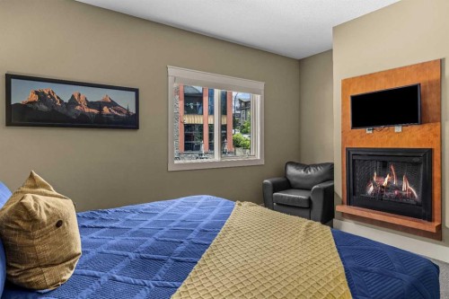 103-191 Kananaskis Way, Canmore, AB - Indoor Photo Showing Bedroom With Fireplace