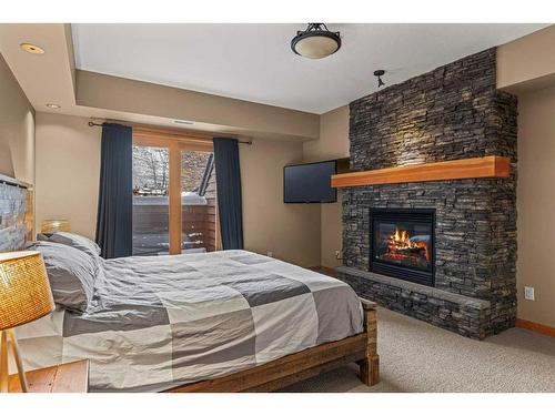 1306-101A Stewart Creek Landing, Canmore, AB - Indoor Photo Showing Bedroom With Fireplace