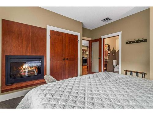105-187 Kananaskis Way, Canmore, AB - Indoor Photo Showing Bedroom With Fireplace