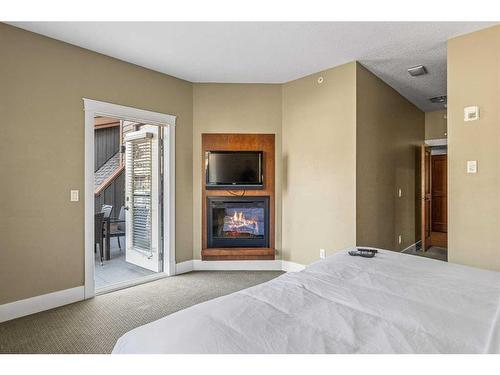 407-187 Kananaskis Way, Canmore, AB - Indoor Photo Showing Bedroom With Fireplace