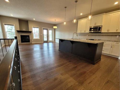 26 Stone Garden Crescent, Carstairs, AB - Indoor Photo Showing Kitchen With Fireplace