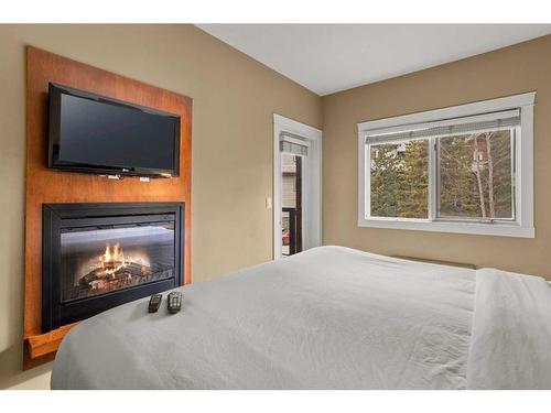 107Bf-187 Kananaskis Way, Canmore, AB - Indoor Photo Showing Bedroom With Fireplace