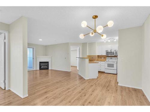 8317-304 Mackenzie Way Sw, Airdrie, AB - Indoor Photo Showing Kitchen With Fireplace