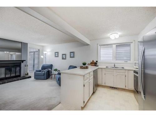 16 Woodmont Green Sw, Calgary, AB - Indoor Photo Showing Kitchen With Fireplace With Double Sink