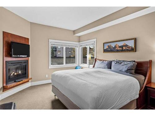 106-173 Kananaskis Way, Canmore, AB - Indoor Photo Showing Bedroom With Fireplace