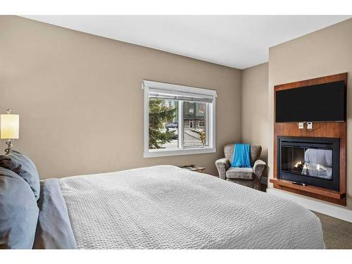 106-173 Kananaskis Way, Canmore, AB - Indoor Photo Showing Bedroom With Fireplace