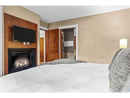 301-173 Kananaskis Way, Canmore, AB - Indoor Photo Showing Bedroom With Fireplace