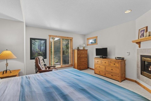 18 Juniper Ridge, Canmore, AB - Indoor Photo Showing Bedroom With Fireplace