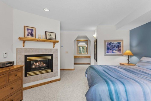 18 Juniper Ridge, Canmore, AB - Indoor Photo Showing Bedroom With Fireplace