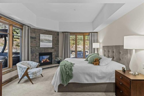 303-150 Stonecreek Road, Canmore, AB - Indoor Photo Showing Bedroom With Fireplace
