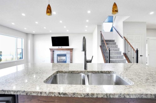 85 Boulder Creek Manor Se, Langdon, AB - Indoor Photo Showing Kitchen With Fireplace With Double Sink