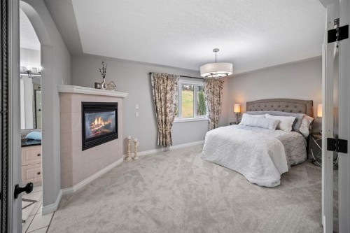 187 Gleneagles View, Cochrane, AB - Indoor Photo Showing Bedroom With Fireplace