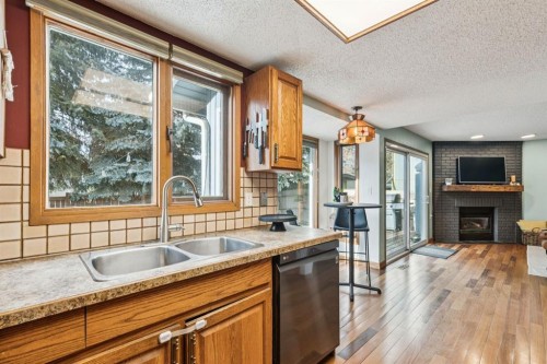 715 Coach Bluff Crescent Sw, Calgary, AB - Indoor Photo Showing Kitchen With Fireplace With Double Sink