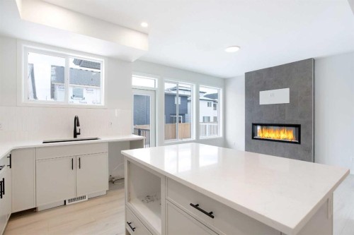 49 Creekside Passage Sw, Calgary, AB - Indoor Photo Showing Kitchen With Fireplace