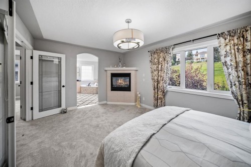 187 Gleneagles View, Cochrane, AB - Indoor Photo Showing Bedroom With Fireplace