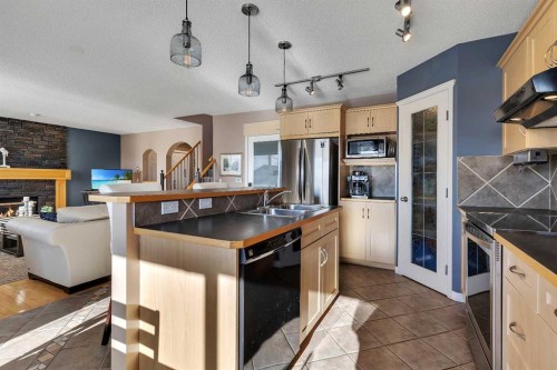 133 Rocky Ridge Heath Nw, Calgary, AB - Indoor Photo Showing Kitchen With Fireplace With Double Sink