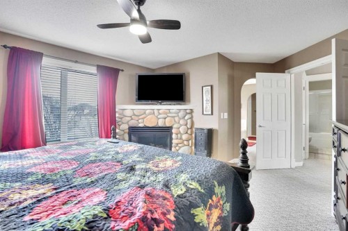 251 Lakeview Cove, Chestermere, AB - Indoor Photo Showing Bedroom With Fireplace