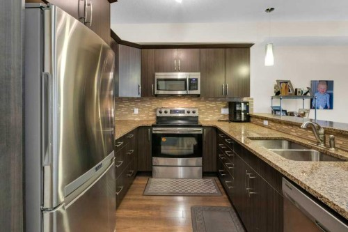 2104-15 Sunset Square, Cochrane, AB - Indoor Photo Showing Kitchen With Stainless Steel Kitchen With Double Sink With Upgraded Kitchen