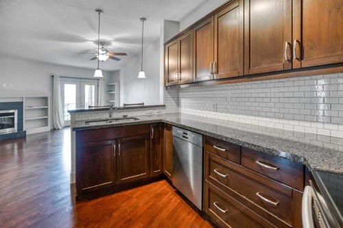 213-77 George Fox Trail West, Cochrane, AB - Indoor Photo Showing Kitchen With Fireplace
