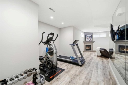 244 Cove Road, Chestermere, AB - Indoor Photo Showing Gym Room With Fireplace