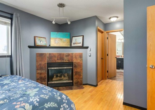 244 Stonegate Close Nw, Airdrie, AB - Indoor Photo Showing Bedroom With Fireplace