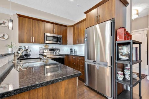 2110-15 Sunset Square, Cochrane, AB - Indoor Photo Showing Kitchen With Stainless Steel Kitchen With Double Sink With Upgraded Kitchen