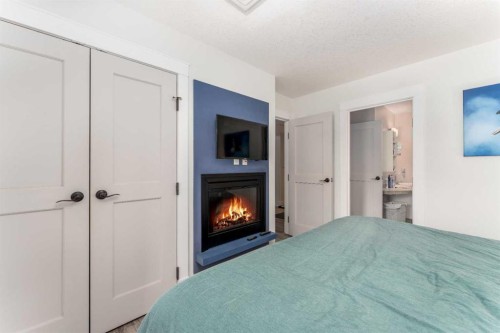 213-173 Kananaskis Way, Canmore, AB - Indoor Photo Showing Bedroom With Fireplace