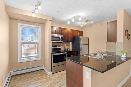 7202-403 Mackenzie Way Sw, Airdrie, AB - Indoor Photo Showing Kitchen With Stainless Steel Kitchen With Double Sink